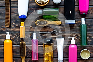 Cosmetics for hair with oil, scissors, comb, conditioner and shampoo in bottle on wooden background top view pattern