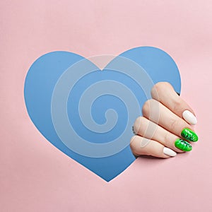 Cosmetics hand makeup, beautiful nails manicure, nail Polish, advertising on colored paper background. Fingers with bright colored