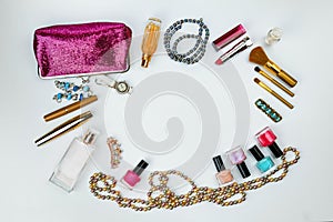 Cosmetics, jewelry, perfumes and a beautiful pink cosmetic bag on a white background, top view