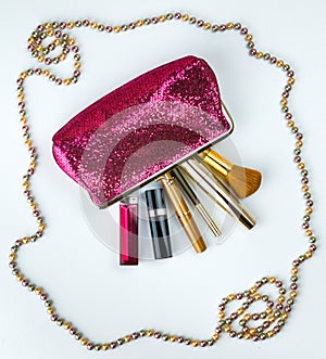 Cosmetics, jewelry, perfumes and a beautiful pink cosmetic bag on a white background, top view