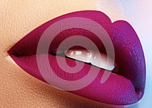 Cosmetics, makeup. Bright lipstick on lips. Closeup of beautiful female mouth with purple lip makeup. Part of face