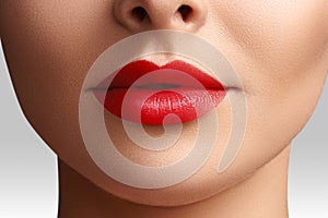 Cosmetics, makeup. Bright lipstick on lips. Closeup of beautiful female mouth with red lip makeup. Clean skin model