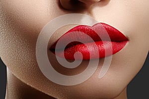 Cosmetics, makeup. Bright lipstick on lips. Closeup of beautiful female mouth with red lip makeup. Clean skin model