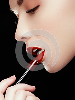 Cosmetics and makeup. Perfect lip makeup. Fashion model applying lipstick. Beautiful young woman