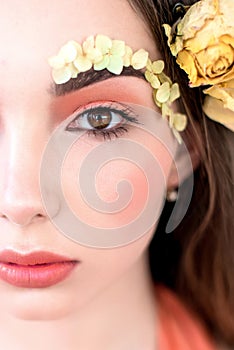 Cosmetics and manicure. Close-up portrait of attractive woman with dry flowers on her face and hair, pastel color, perfect make-up