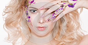 Cosmetics and manicure. Close-up portrait of attractive woman with dry flowers on her face, pastel color of nail design