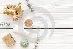 Cosmetics with natural herbal and ginger ingredients on white wooden background top view copyspace