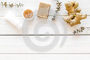 Cosmetics with natural herbal and ginger ingredients on white wooden background top view copyspace