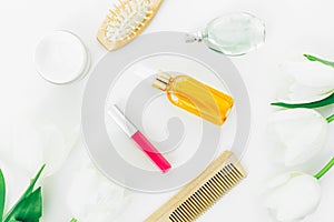 Cosmetics, perfume, combs and tulips flowers on white background. Beauty blogger composition. Flat lay, top view