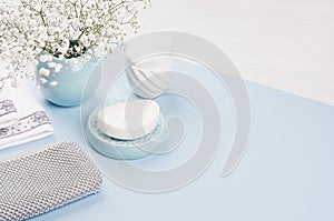 Cosmetics products background - set for body and skin care, blue ceramic bowl, silver accessories, flowers on white wood, color.