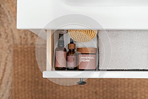 cosmetics products and clean towel in cupboard box, above view