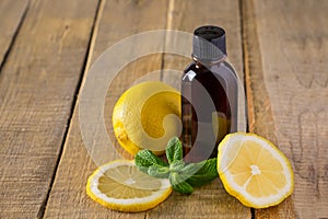 Cosmetics for spa therapy. Bottle of aromatic oil with lemon and mint on wooden background
