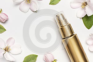 Cosmetics springtime Concept. Cosmetics, spring white flowers green leaves on light background. Cosmetic mock up gold