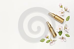 Cosmetics springtime Concept. Cosmetics, spring white flowers green leaves on light background. Cosmetic mock up gold