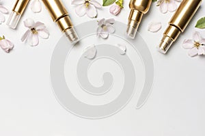 Cosmetics springtime Concept. Cosmetics, spring white flowers green leaves on light background. Cosmetic mock up gold