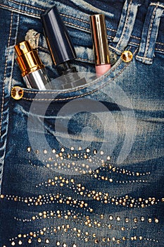 Cosmetics sticks out of the pocket of his jeans with rhinestones