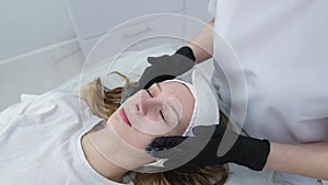 Cosmetologist applies a woman a therapeutic mask on her face. Woman in a spa salon on cosmetic procedures for facial