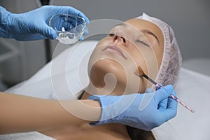 Cosmetologist applying chemical peel product on client`s face in salon