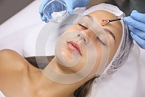 Cosmetologist applying chemical peel product on client`s face in salon