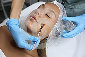 Cosmetologist applying chemical peel product on client`s face in salon