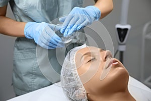 Cosmetologist applying chemical peel product on client`s face in salon