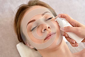 Cosmetologist applying cream on girl's face. The concept of facial skin care photo