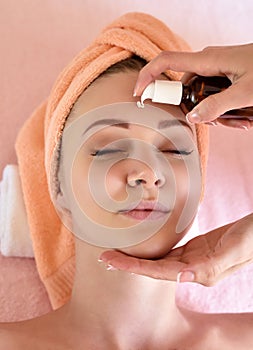 Cosmetologist applying cream on girl's face. The concept of facial skin care photo