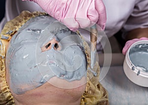 Cosmetologist applying facial mask to problem skin. young woman having face cleaning procedure