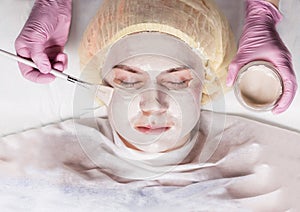 Cosmetologist applying facial mask to problem skin. young woman having skin procedures cleaning