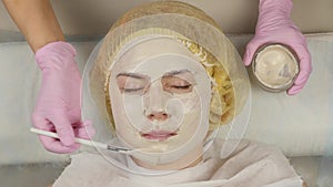 Cosmetologist applying facial mask to problem skin. young woman having skin procedures cleaning. 4K