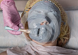 Cosmetologist applying facial mask to problem skin. young woman having face cleaning procedure