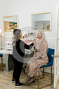 Cosmetologist applying foundation makeup to a blond woman in a makeup chair