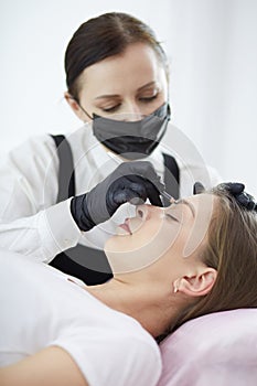 Cosmetologist applying permanent make up on eyebrows