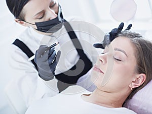 Cosmetologist applying permanent make up on eyebrows