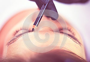 Cosmetologist applying permanent make up on eyebrows