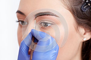 Cosmetologist applying special permanent make up of eyebrows.