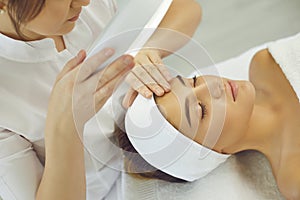 Cosmetologist checking skin elasticity and making examination for young relaxing woman photo