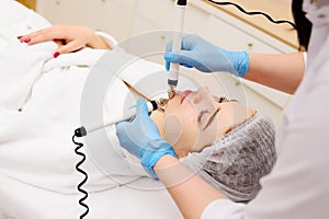 cosmetologist conducts microcurrent facial therapy for a young woman using a device in a beauty salon. Hardware