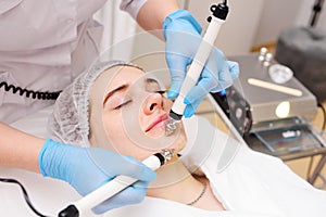 cosmetologist conducts microcurrent facial therapy for a young woman using a device in a beauty salon. Hardware