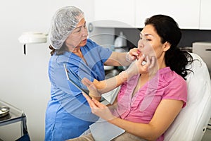 Cosmetologist consulting woman before procedures for lip augmentation