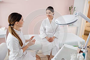 Cosmetologist discussing vitamins with smiling young woman