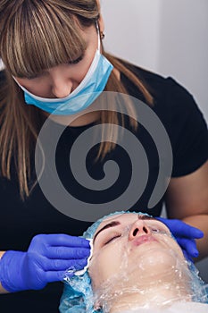 cosmetologist disinfects the skin of the face before the mesotherapy procedure