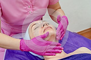 Cosmetologist doctor applies cream to woman face in beauty salon. Preparation for the procedure of rejuvenation, restoration of