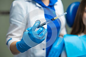 Cosmetologist doctor in blue medical gloves holding syringe with injections before treatment, closeup. Beautician on mesotherapy