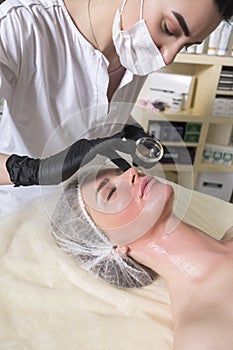 Cosmetologist doctor do enzyme theraphy procedure to a woman in her clinic. She wear glowes and mask