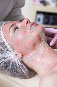 Cosmetologist doctor do enzyme theraphy procedure to a woman in her clinic. She wear glowes and mask