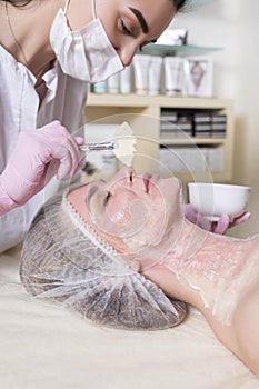 Cosmetologist doctor do enzyme theraphy procedure to a woman in her clinic. She wear glowes and mask