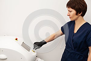 Cosmetologist doctor prepares to laser epilate client in beauty studio