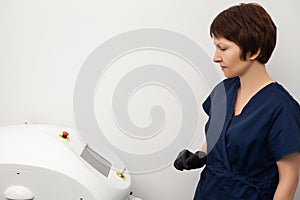 Cosmetologist doctor prepares to laser epilate client in beauty studio