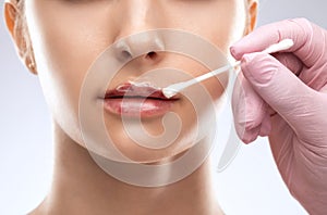 Cosmetologist does injections for lips augmentation and anti wrinkle in the nasolabial folds of a beautiful woman. Women's